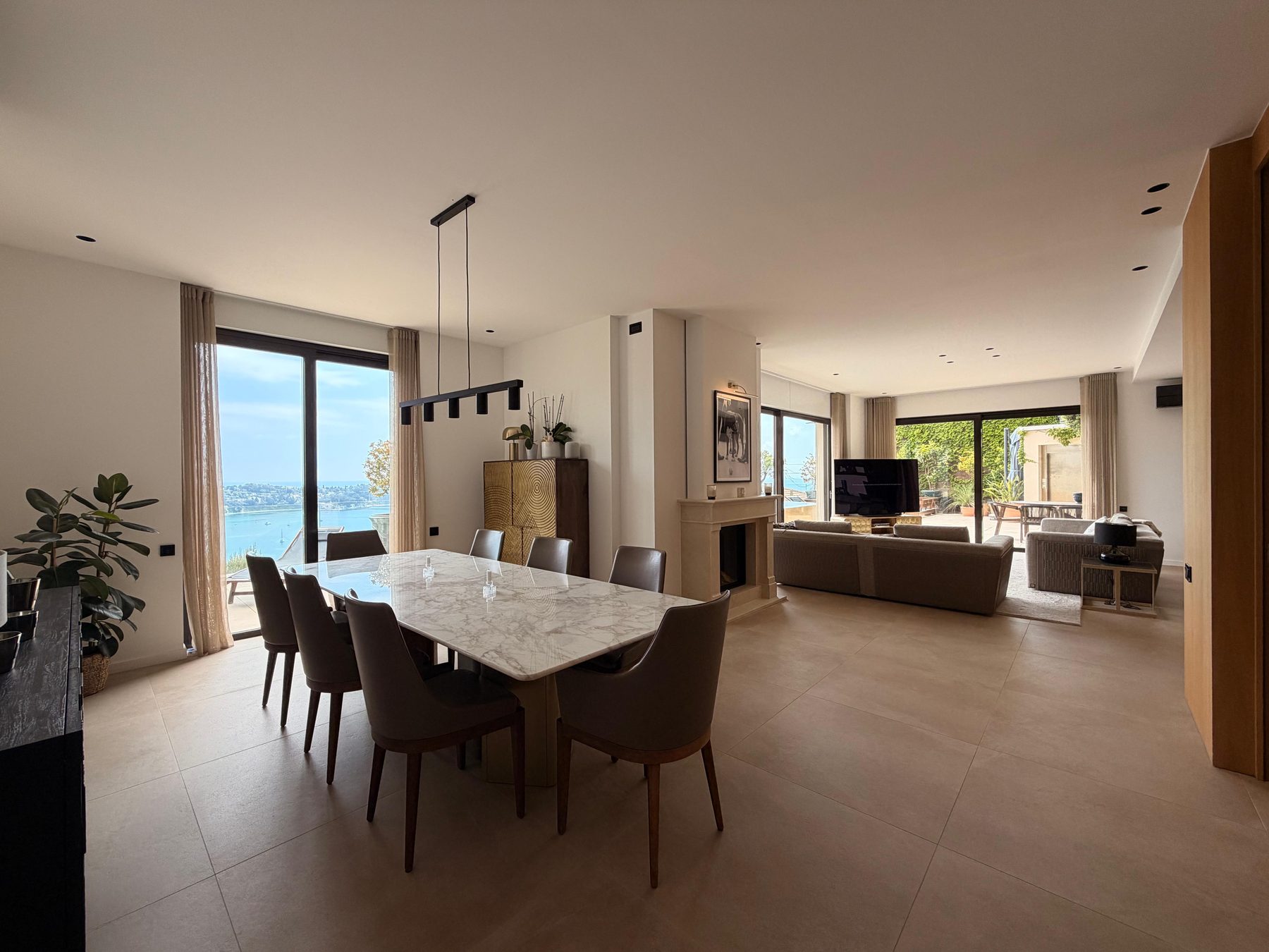 Marble dining table beside floor-to-ceiling windows framing the bay of Villefranche