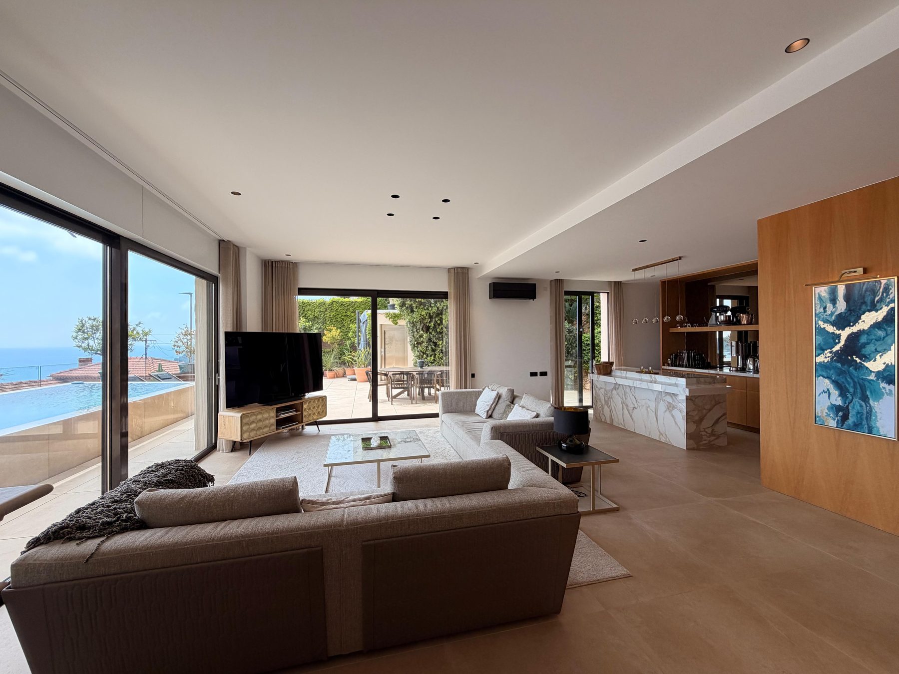 Open-plan living room with sliding glass doors onto the terrace, pool and the sea beyond
